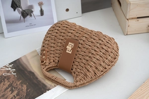 Detailansicht der handgewebten Strohtasche mit braunem Lederriemen und goldenem Schloss