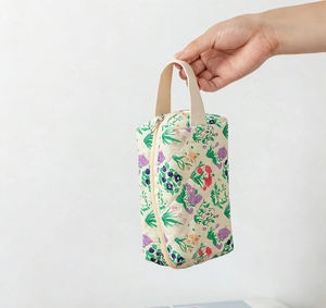 Borsa cosmetica trapuntata a fiori viola e rossi con ampio manico tenuta in mano