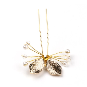 Macro detail of bridal U-shaped hair pin with golden leaves, pearls and crystals