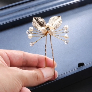 Detailed view of handmade golden leaf hair fork with white pearls and sparkling rhinestones