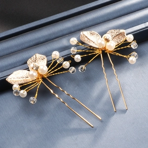 Detailed macro view of golden leaf hair pins with pearls and crystal beads on blue fabric