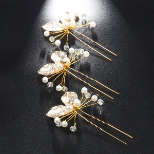 Detail view of three golden U-shaped hair pins with pearls and crystal leaf designs