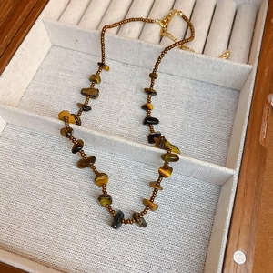 Collana artigianale con pietre occhio di tigre e chiusura dorata su vassoio in lino