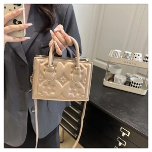 Detail of beige shoulder bag with 3D embossed floral patterns and golden hardware