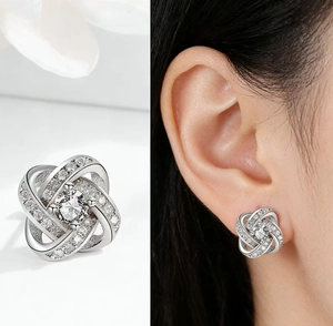 Dettaglio di orecchini a lobo quadrifoglio in argento con pavé di zirconi e nodo design