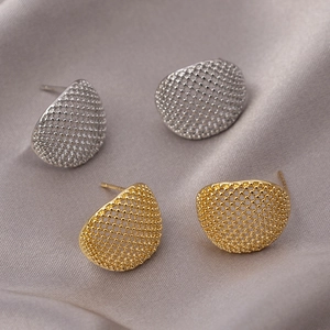 Modern gold and silver textured dome stud earrings set on elegant silk fabric background