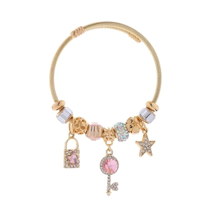 Dettaglio del bracciale dorato con perline e ciondoli a stella rosa e chiave