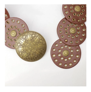 Macro detail of western vintage belt showing carved sunflower gold buckle and brown leather