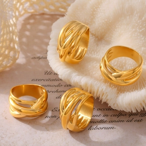 Chunky gold titanium steel rings with irregular intertwined lines on a white coral display