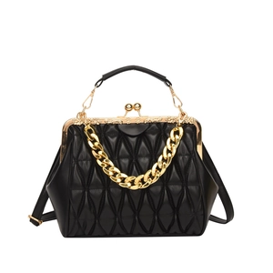 Detail of black quilted leather crossbody bag featuring gold metal frame and thick chain