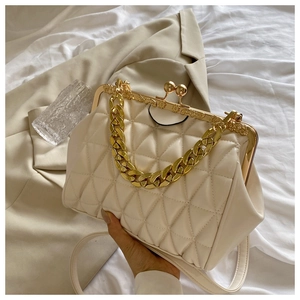 Detail of cream quilted handbag featuring gold chunky chain and vintage kiss lock clasp