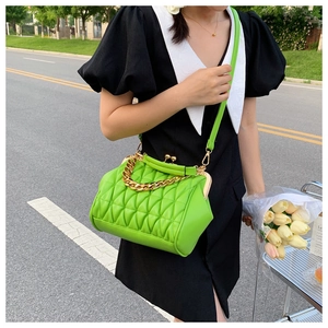 Close-up of vibrant green quilted handbag featuring vintage gold clasp and chunky chain link
