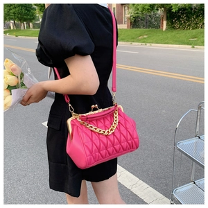 Detail of rose red quilted crossbody bag with gold chain and vintage metal clasp closure