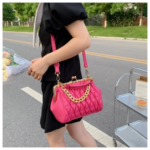 Detail view of pink quilted crossbody bag with gold chain and kiss-lock closure