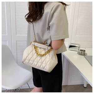 Detail of cream quilted bag with gold kissing lock and metal chain handle