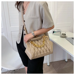Detail of beige quilted crossbody bag with vintage clasp and chunky gold chain strap