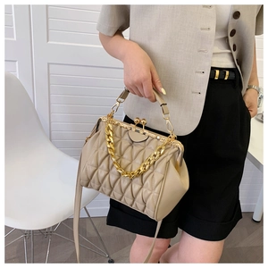 Detail of pleated beige shell bag featuring gold chain strap and metal clasp closure