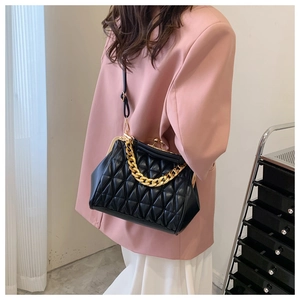 Detail of black quilted chain bag with gold buckle and textured leather on a model
