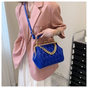 Detail of royal blue shell bag featuring diamond quilted texture and gold metal chain strap