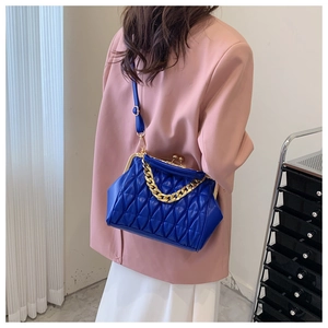 Detail of royal blue quilted shell bag with gold chain strap and metal clasp closure
