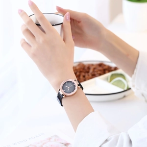 Detail of rose gold quartz watch with black Milanese strap worn in a lifestyle setting