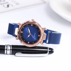 Detail of rose gold quartz watch with faceted glass dial and blue Milanese mesh band
