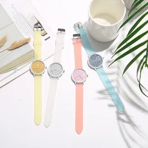 Close-up of four colorful glitter quartz watches with shimmering straps on a desk