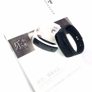 Close-up of black and white smart fitness trackers with silicone straps on a white book