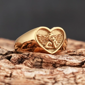 Bague cœur vintage plaquée or avec relief d'ange chérubin sur une surface en bois naturel