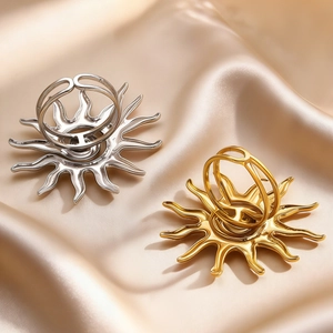 Detailed view of hollow sunflower open rings in gold and silver on silk fabric