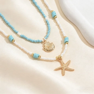 Dettaglio di collana a strati a tema marino con stella marina, conchiglia e perline