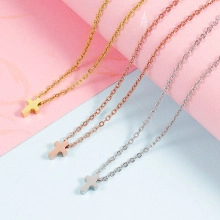 Close-up of minimalist cross necklaces in gold, rose gold and silver polished steel
