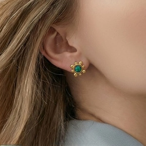 Close-up of vintage gold hoop earrings with green gemstone and leopard print oil drip detail