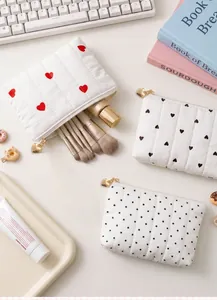 Quilted pouch storage capacity shown with makeup brushes and cosmetics on white desk