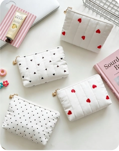 Close-up of quilted heart pattern vanity pouches with heart-shaped gold zipper pulls