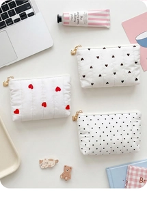 Detail of quilted cotton coin purse featuring heart patterns and gold heart zipper pull