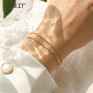Detail of layered gold double-strand bracelet with delicate beads and flat snake chain