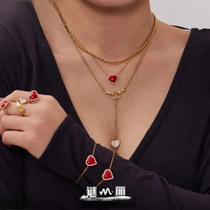 Detail view of red heart jewelry set with layered gold necklaces and rings on a model