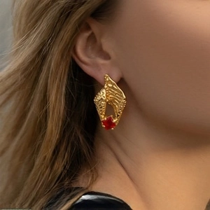 Close-up of vintage gold hammered earring with a square red zircon on female model