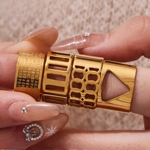 Detailed close-up of four gold vintage hollow rings with geometric patterns on a hand