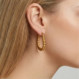 Detail of 18k gold plated textured hoop earring on model with elegant wave pattern