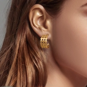 Detailed close-up of golden hollow geometric hoop earrings with a modern mesh pattern