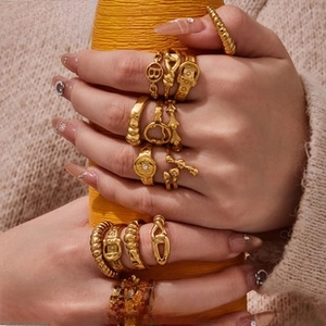 Close-up of vintage gold ring set featuring B letter and chain link designs on hands
