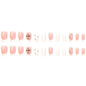 Detail of French press-on nails with silver crosses and rhinestones on light pink base