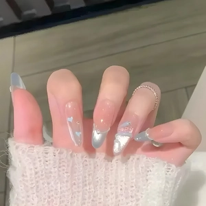 Detail of long almond press-on nails featuring blue cat-eye effect and silver glitter