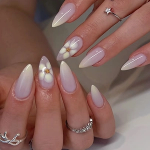 Detailed shot of lavender gradient almond nails with white floral art and gold beads