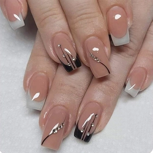 Detail of nude coffin nails with French white tips, black stripes and rhinestone accents