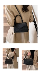 Detail of black faux leather crossbody bag with 3D floral embossing and gold clasp