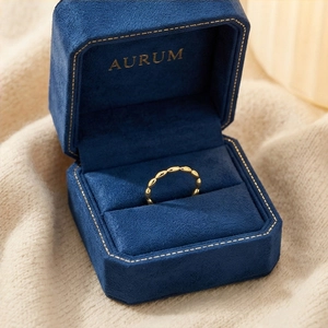 Close-up of a minimalist 18k gold grain ring in a premium blue velvet AURUM jewelry box