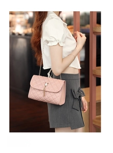 Pink quilted chain bag with pearl and tassel details shown in an indoor lifestyle setting